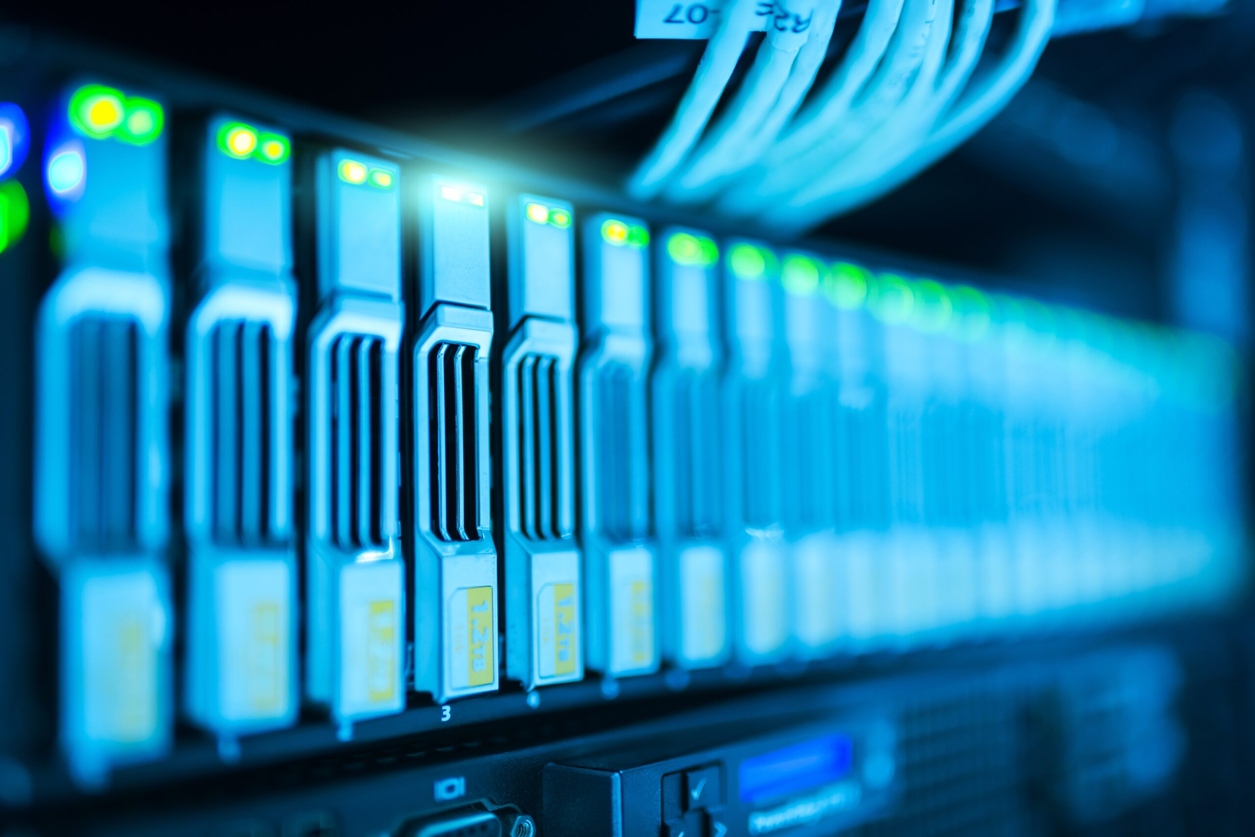 Close view of glowing blue network cables plugged into a rack of switches