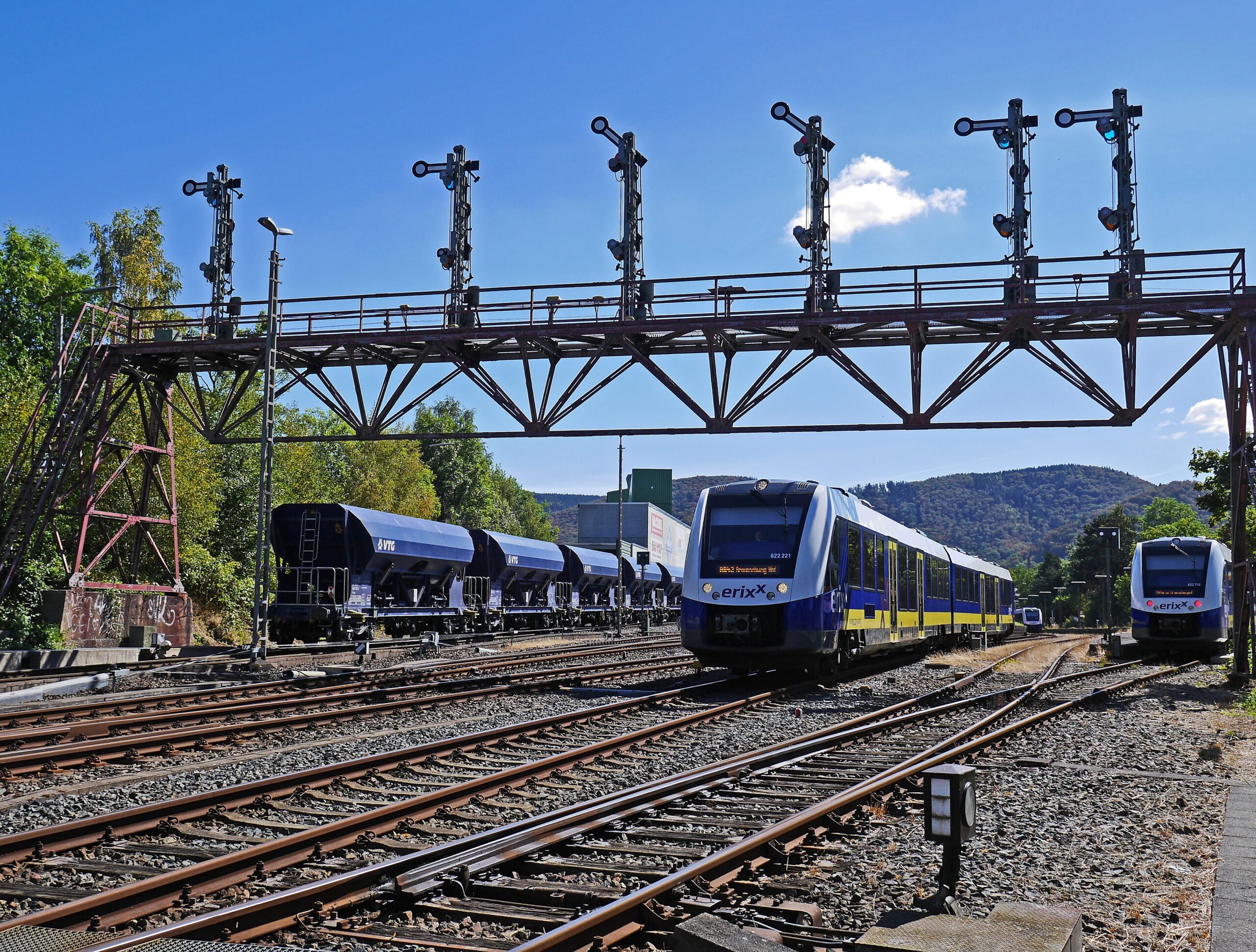 Gantry with cameras and signals above railway tracks with a train passing