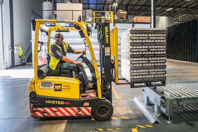 Forklift operator moving pallets in a warehouse