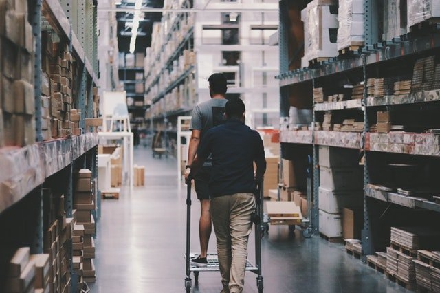Warehouse workers walking along a stocked aisle while picking orders
