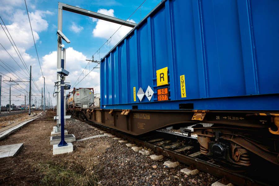 Rail OCR camera mast reading a container on a passing freight wagon