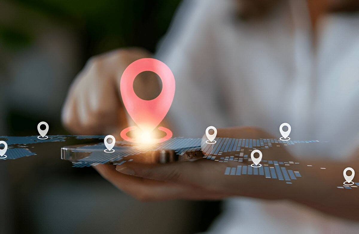 Hand holding a smartphone showing a map with GPS location pins for tracked shipments