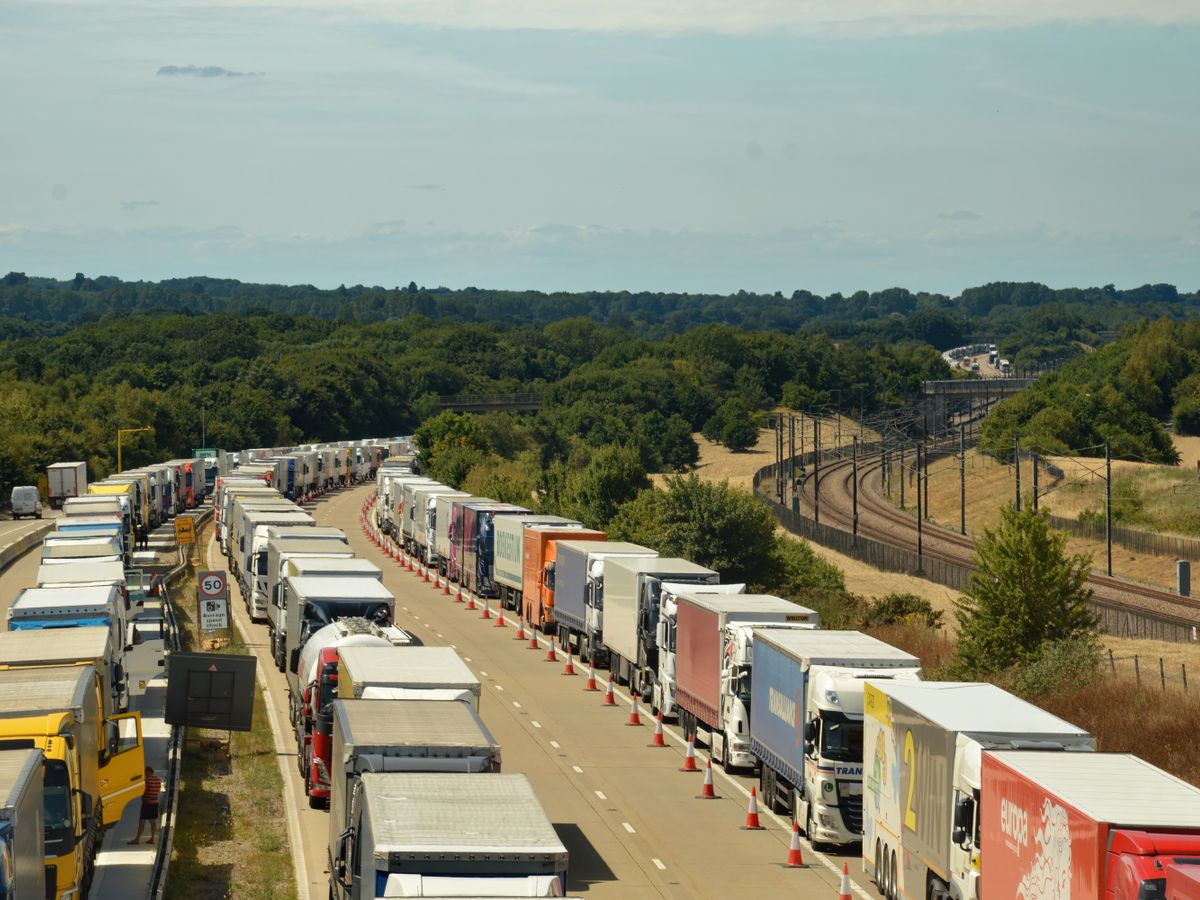 Long queue of trucks waiting on the road outside a site